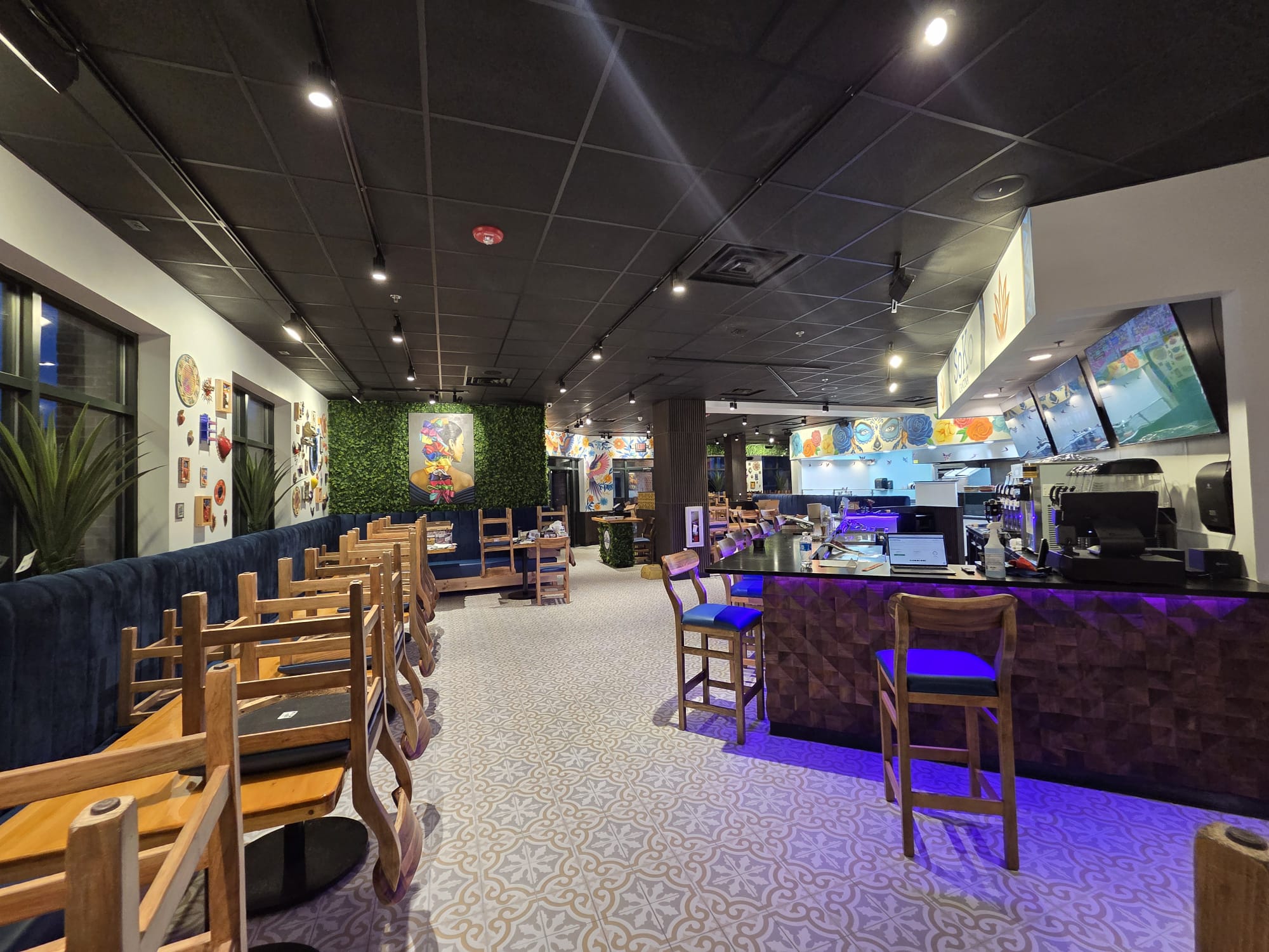 The bar at Soko Cantina with carved wood front and purple accent lighting
