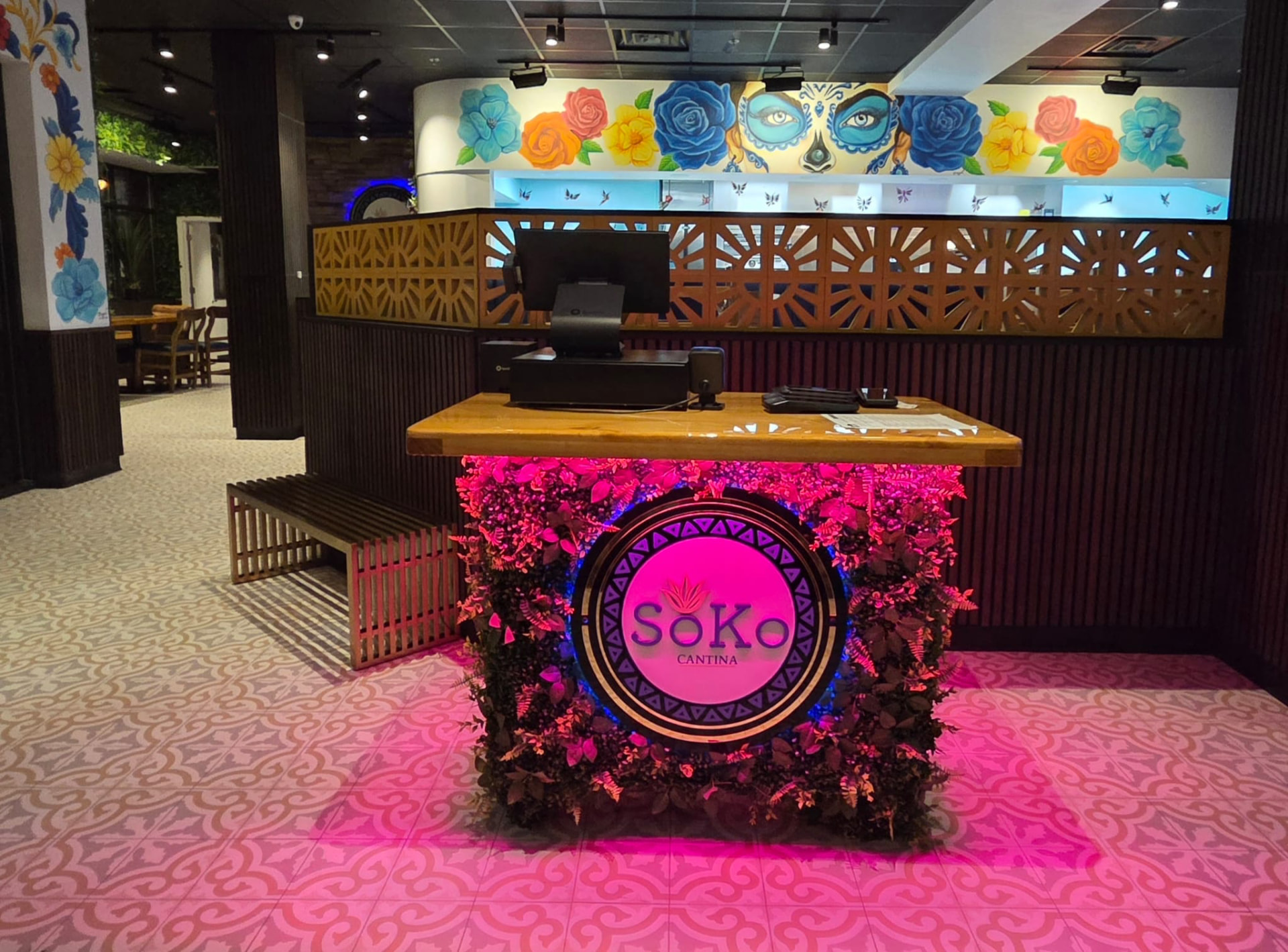 Soko Cantina entry host stand with illuminated logo and floral mural