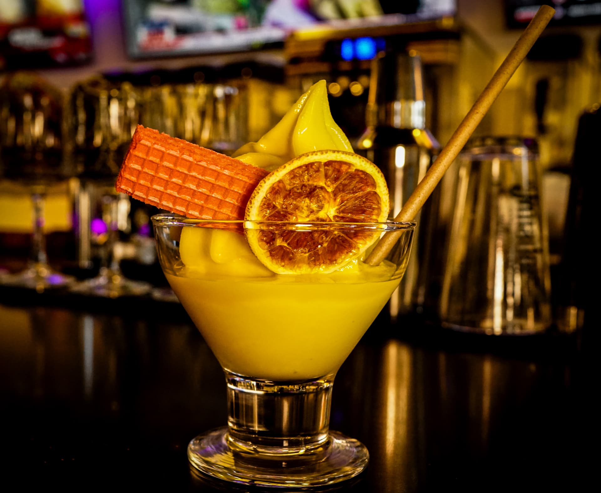 Frozen golden drink topped with a citrus wheel and pink wafer